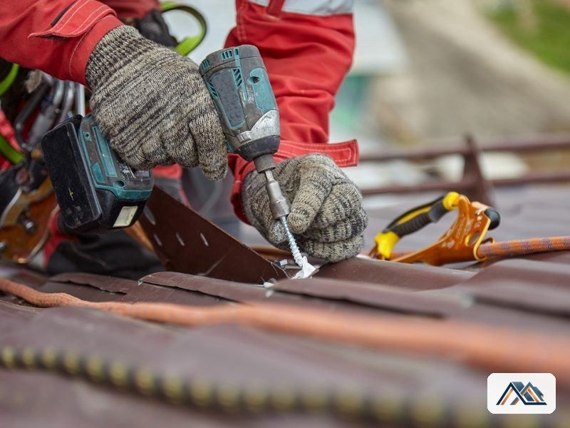 Equipo de cubiertas en Lugo Operario fijando una pieza de cubierta con atornillador y guantes de trabajo en Lugo